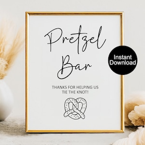 May include: A framed sign with gold trim and a white background. The sign reads "Pretzel Bar" in elegant script, with "Thanks for helping us tie the knot!" below. A pretzel graphic is at the bottom. A black circle with "Instant Download" is on the right.