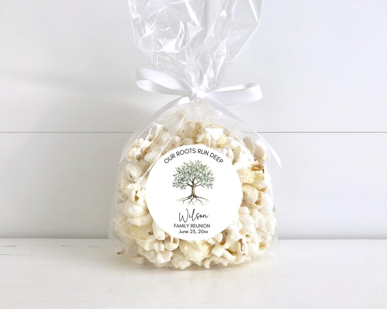 May include: A clear cellophane bag filled with popcorn, tied with a white ribbon. A round sticker on the bag features a tree illustration and the text "OUR ROOTS RUN DEEP" and "Wilson FAMILY REUNION June 23, 20xx."