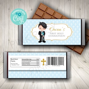 Puede incluir: Un envoltorio de chocolate azul y dorado con un niño de dibujos animados con traje sosteniendo un libro. El envoltorio dice "Owen's First Holy Communion".