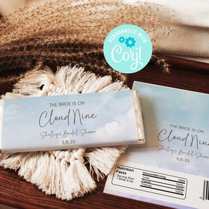 May include: A blue and white chocolate bar wrapper with the text "The Bride is on Cloud Nine" and "Shelley's Bridal Shower 3.31.25". The wrapper has a sky and cloud design.