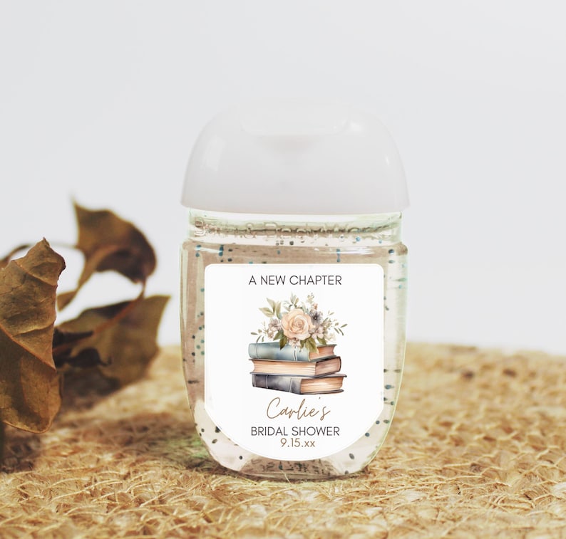 May include: Clear hand sanitizer bottle with a white cap and a label that reads "A New Chapter." The label features a floral design above a stack of books and the text "Carlie's Bridal Shower 9.15.xx."