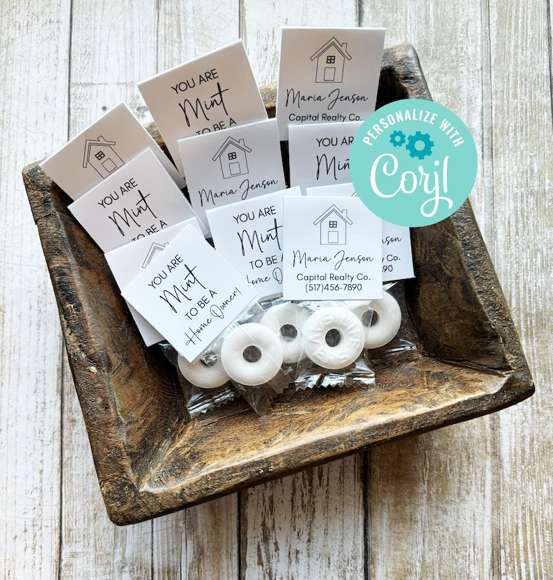 May include: A wooden tray filled with small white bags containing white mints and small white cards with the text "You are a mint to be a home owner!" and a house icon. The cards also include the name "Maria Jenson" and the text "Capital Realty Co. (517)456-7890".