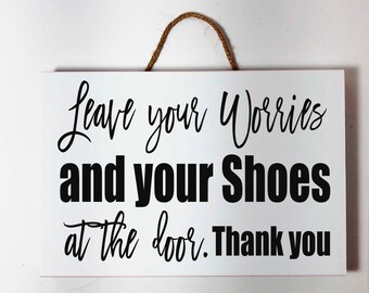 May include: White rectangular wooden sign with black text that reads "Leave your Worries and your Shoes at the door. Thank you." The sign has a brown rope for hanging.