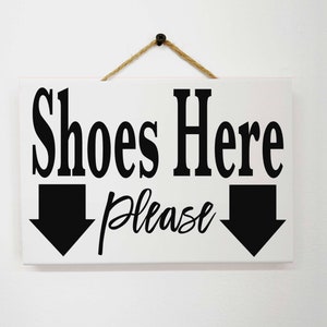 Shoes Here Please sign with arrows pointing to shoe bin rack in entry foyer