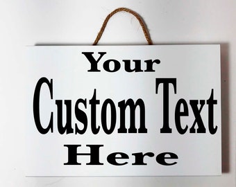 May include: White wooden sign with a brown twine hanger. The sign has black text that reads "Your Custom Text Here".