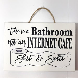 May include: White wooden sign with black text that reads "This is a Bathroom not an Internet Cafe" with a cartoon toilet paper roll and the text "Shit & Split" underneath.