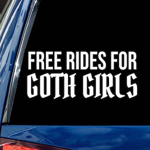 May include: White vinyl sticker with the text "FREE RIDES FOR GOTH GIRLS" in a gothic font style. The sticker is applied to the back window of a blue car.