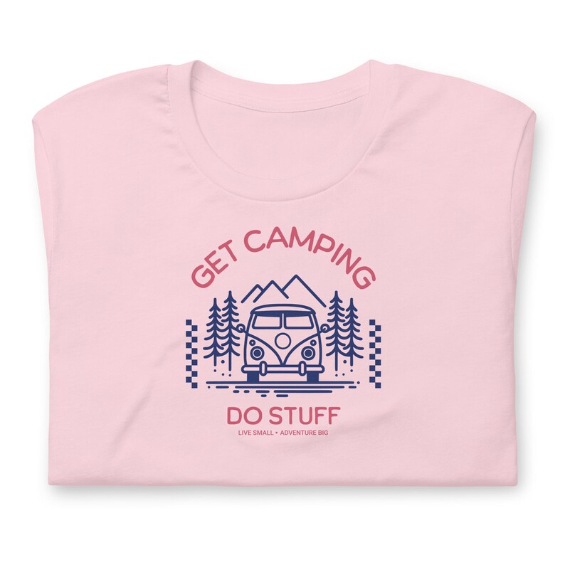 Pode incluir: Uma t-shirt rosa claro com um gr&aacute;fico azul escuro de uma carrinha de campismo, pinheiros e montanhas. O texto diz GET CAMPING DO STUFF e LIVE SMALL + ADVENTURE BIG. O design inclui um padr&atilde;o de xadrez nos lados esquerdo e direito.