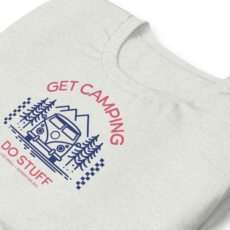 Pode incluir: Uma t-shirt cinzenta clara mesclada com um gr&aacute;fico azul-escuro e rosa. O design inclui uma carrinha de campismo, pinheiros e montanhas com o texto GET CAMPING DO STUFF e o texto mais pequeno LIVE SMALL ADVENTURE BIG com detalhes axadrezados.
