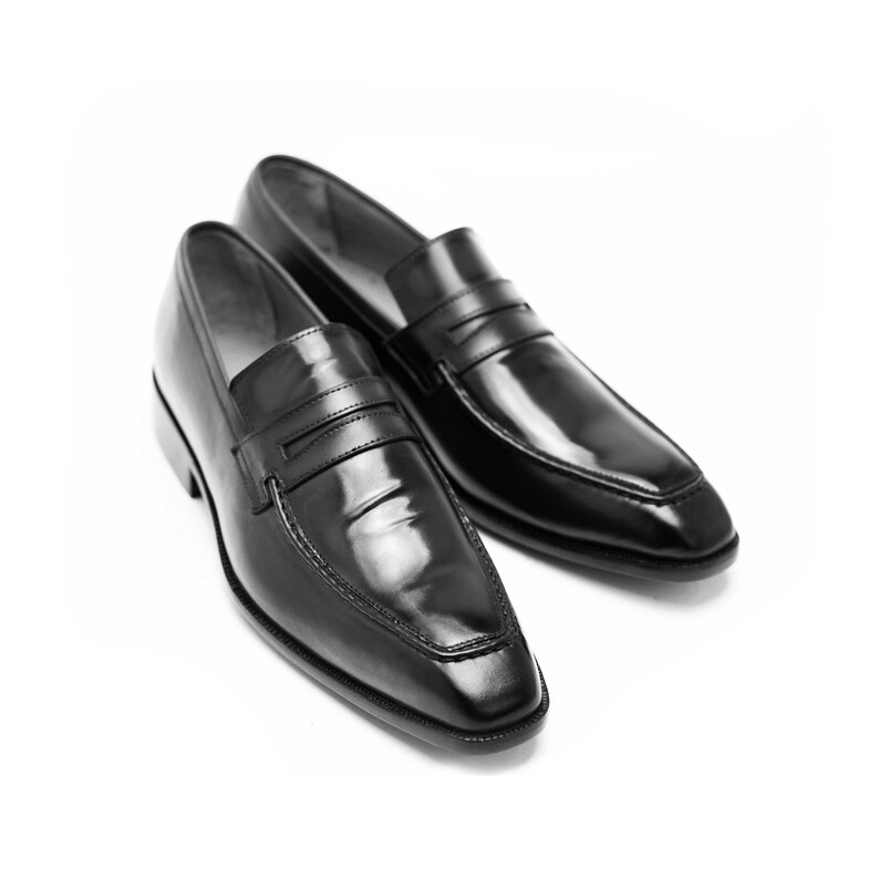 Puede incluir: Un par de mocasines de cuero negro con un dise&ntilde;o sencillo. Los mocasines tienen una punta puntiaguda y una sola correa sobre el empeine.