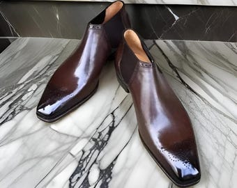 May include: A pair of brown leather ankle boots with a pointed toe and elastic side panels. The boots have a polished finish and a subtle brogue detail.