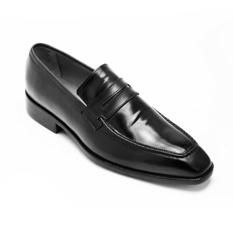 Puede incluir: Zapatos de vestir de cuero negro con una sola correa en el empeine.