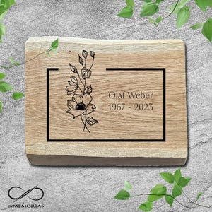 Peut inclure: Plaque rectangulaire en bois avec un motif floral et le nom "Olaf Weber" et les dates "1967 - 2023" gravés en noir. La plaque a un fini grain de bois naturel et un bord noir. Le logo "INMEMORIAS" est en bas.