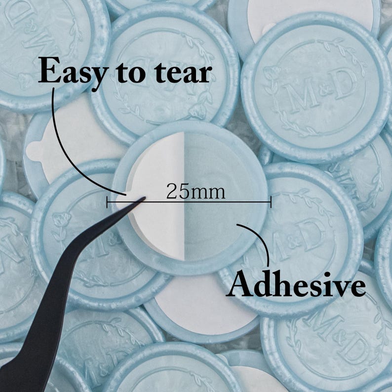 May include: A close-up of a pile of light blue round wax seals with a white adhesive backing. The seals are 25mm in diameter and have the initials "M&D" embossed on them. The text "Easy to tear" and "Adhesive" are written on the image.