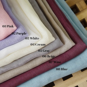 Puede incluir: Un conjunto de ocho muestras de tela en diferentes colores, incluyendo rosa, morado, blanco, crema, gris, beige, vino y azul. Las muestras están etiquetadas con sus colores correspondientes.