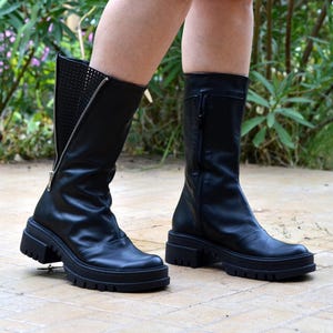 K&ouml;nnte beinhalten: Schwarze Lederstiefel mit seitlichem Rei&szlig;verschluss und einer dicken Plateau-Sohle.