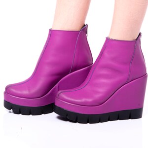 May include: A pair of purple wedge ankle boots with a black platform sole.