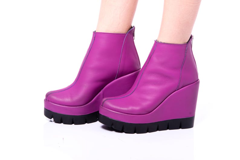 May include: A pair of purple wedge ankle boots with a black platform sole.