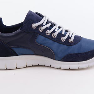 Op de afbeelding: Blauwe en marineblauwe sneakers met witte veters en een witte zool.