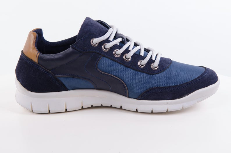 Op de afbeelding: Blauwe en marineblauwe sneakers met witte veters en een witte zool.