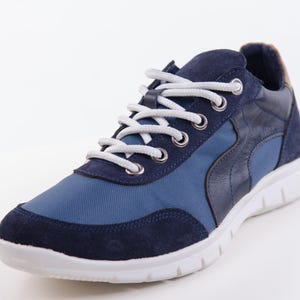 Op de afbeelding: Een paar blauwe en donkerblauwe sneakers met witte veters. De sneakers hebben een witte zool en een blauwe en donkerblauwe bovenkant.