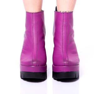 May include: A pair of purple platform ankle boots with a black sole.