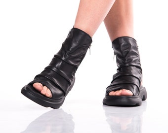 May include: Black leather ankle boots with a zipper on the side and an open toe design. The boots have a chunky platform sole.