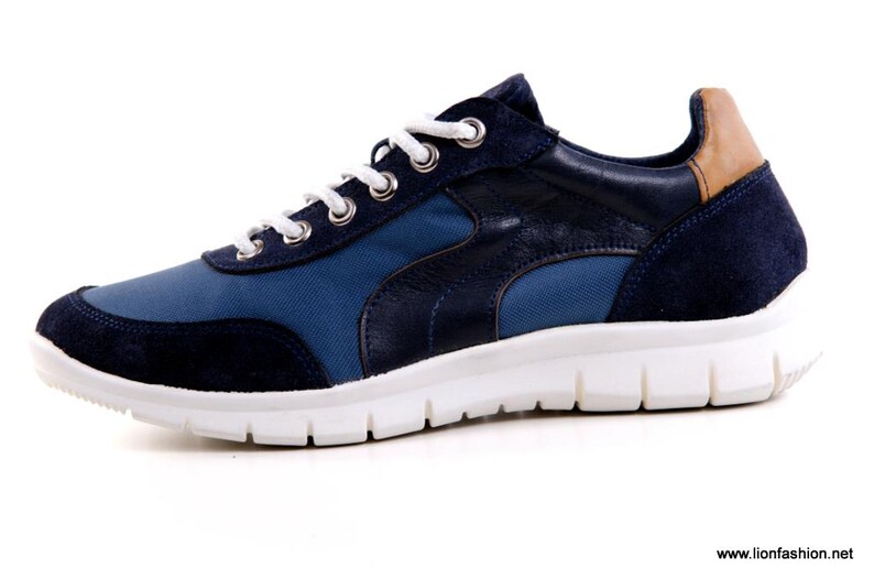 Op de afbeelding: Een paar blauwe en bruine sneakers met een witte zool. De sneakers hebben een su&egrave;de neus en een canvas bovenwerk.