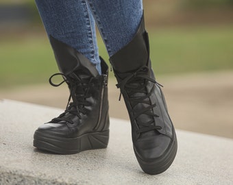 May include: A pair of black leather ankle boots with laces and a zipper. The boots have a thick platform sole.