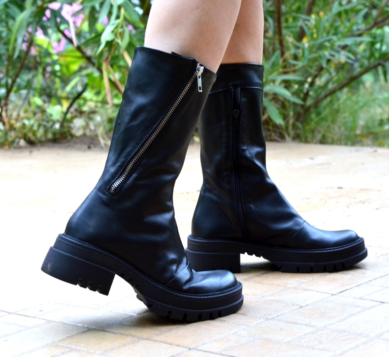K&ouml;nnte beinhalten: Schwarze Lederstiefel mit einem dicken Absatz und einem seitlichen Rei&szlig;verschluss. Die Stiefel haben eine leicht spitz zulaufende Spitze.