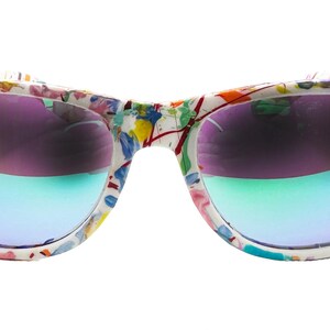 Puede incluir: Gafas de sol blancas con montura con estampado floral colorido. Las lentes tienen un efecto degradado, pasando del morado al azul y al verde. Un accesorio vibrante.