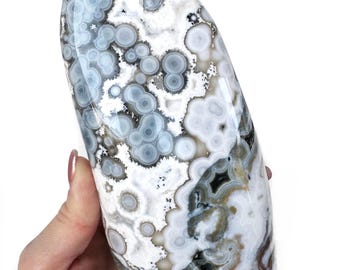 May include: A large, white, gray, and brown agate freeform with a unique pattern of circles and swirls. The agate is smooth and polished.