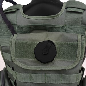 May include: Olive green tactical vest with multiple straps and pouches. Features a black hydration reservoir cap and a black hose. The vest is designed for military or outdoor activities.