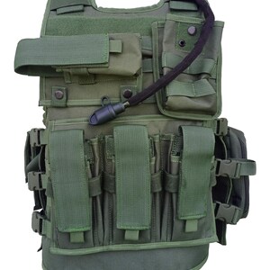 May include: Green tactical vest with multiple pouches, straps, and a hydration system. Features adjustable straps, multiple magazine pouches, and a front closure. The vest is designed for utility and protection.
