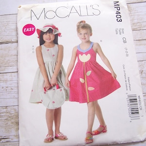 May include: A sewing pattern for a girl's dress with a flower design. The pattern is from McCall's and is labeled MP403. The pattern is for sizes 1-2-3.