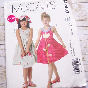 May include: McCall's sewing pattern for a girl's dress, size 4-5-6. The pattern is called "Easy" and features two girls wearing dresses with different floral prints. The pattern number is MP403.