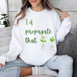 May include: White sweatshirt with the text "I'd propagate that." and two green plant illustrations.