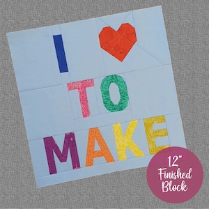 May include: A 12-inch quilt block featuring the words "I love to make" in colourful fabric letters. The letters are arranged in a heart shape with a red heart at the centre.