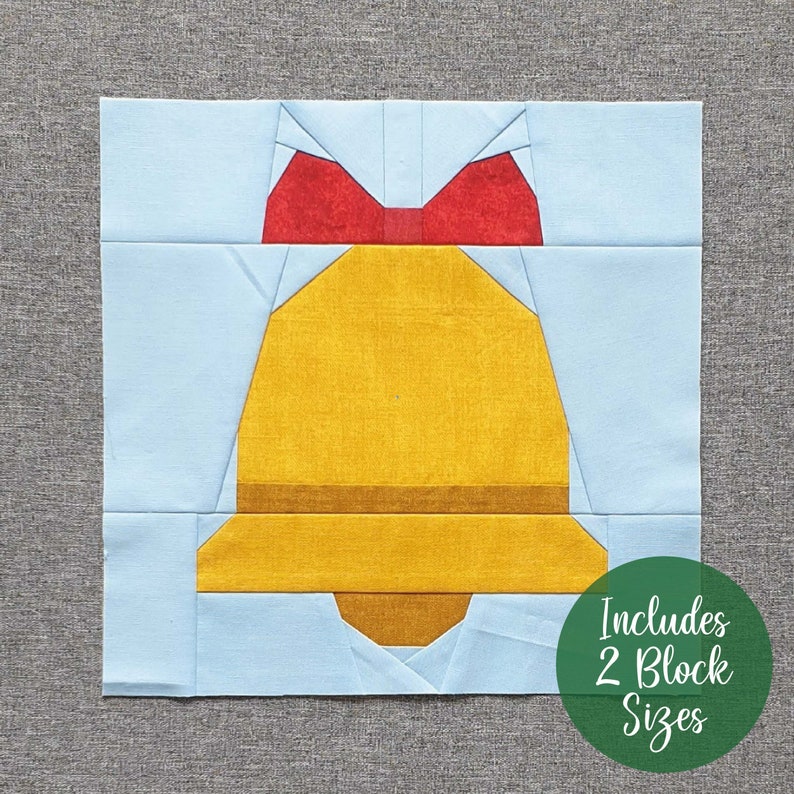 Op de afbeelding: Een papieren patchwork quiltblokpatroon met een gele bel met een rode strik erop. Het patroon omvat twee blokformaten. De tekst "Includes 2 Block Sizes" is gedrukt op een groene cirkel.