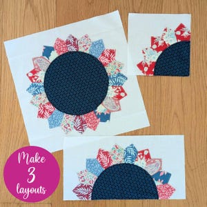 May include: Three white fabric blocks featuring a sunflower design. The sunflowers have a dark blue centre and red, blue, and patterned petals. The text "Make 3 layouts" is in a pink circle.