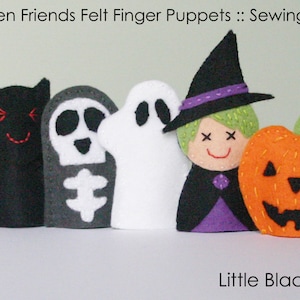 May include: Five felt finger puppets depicting Halloween characters: a black bat, a gray skeleton, a white ghost, a witch with a black hat and purple dress, and an orange pumpkin. The text "Little Black Duck" is printed below the puppets.