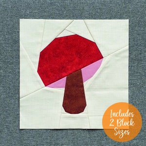 May include: A patchwork quilt block featuring a red and pink mushroom design. The block is made of fabric squares sewn together to create a geometric pattern. The text "Includes 2 Block Sizes" is visible in the lower right corner of the image.