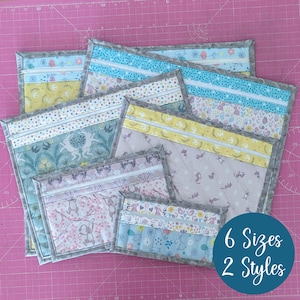 May include: A collection of quilted fabric pouches in various sizes and patterns. The pouches feature floral, animal, and geometric designs in pastel colors, with gray borders. The image includes text that reads "6 Sizes 2 Styles".