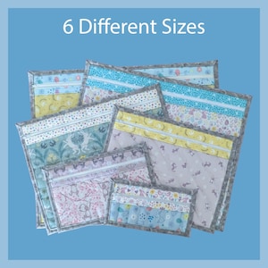 May include: A collection of six quilted fabric pouches in various sizes. Each pouch features a unique combination of pastel colors, floral and animal patterns, and a gray border. The text "6 Different Sizes" is displayed at the top.