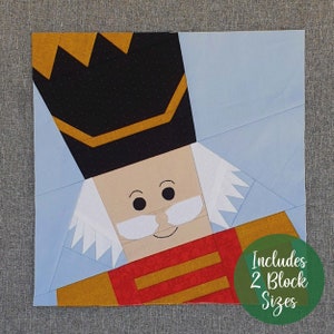 May include: A paper pieced nutcracker quilt block pattern. The pattern includes two block sizes. The nutcracker is wearing a black hat with a gold trim, a red and gold uniform, and a white beard and moustache.