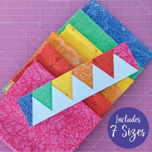 May include: A collection of colorful fabric squares in shades of pink, orange, yellow, green, and blue, arranged on a pink cutting mat. A white and blue triangle pattern is featured in the center. The text "Includes 7 Sizes" is in a purple circle.