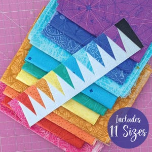 May include: A stack of colorful fabric squares in a rainbow of hues, including pink, orange, yellow, green, blue, and purple. A white, zig-zag shaped piece of fabric sits on top. The image includes the text "Includes 11 Sizes".