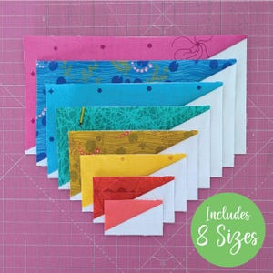 May include: An assortment of eight fabric triangles in different sizes and colours, including pink, blue, yellow, and red, arranged in a stepped pattern. The fabrics feature floral and abstract patterns. A green circle with the text "Includes 8 Sizes" is in the lower right.