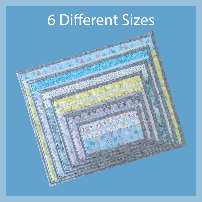 May include: Nested, square fabric placemats in six different sizes. Each placemat features a different patterned fabric, including floral, bunny, and geometric designs. The placemats are bordered with a gray fabric and the text "6 Different Sizes" is at the top.