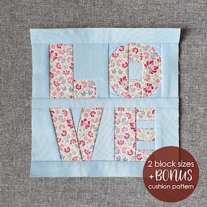 May include: A light blue fabric quilt block with the word "LOVE" spelled out in white fabric with a floral pattern. The quilt block is surrounded by a light blue border. The text "2 block sizes + Bonus cushion pattern" is written in white text on a red circle.